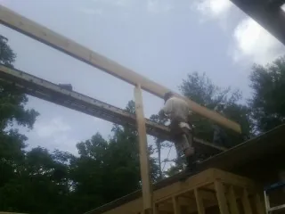 Carpenter setting a ridge beam over a new addition frame — Ice Dam Removal by Roofing Brothers in Waunakee
