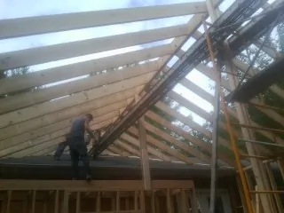 Rafters going up over a new addition with a worker on the wall in Waunakee
