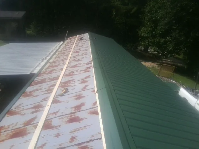 Old rusted panels beside newly installed green metal roofing — Wind Damage Roof Repair by Roofing Brothers in Waunakee