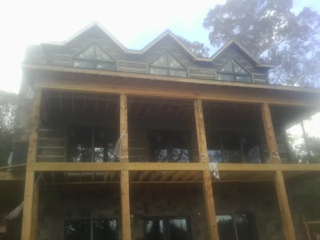 Dormers and porch framing on a large log home under construction — Roof Coating work by our crew in Waunakee