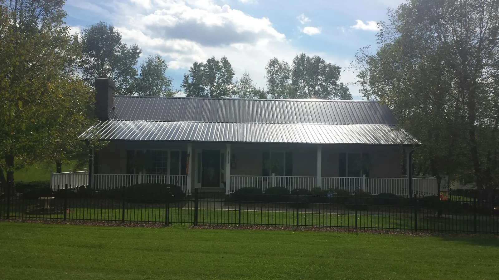 Gray metal roof on a brick ranch with a full width front porch — Gutter Guard Installation work by our crew in Waunakee